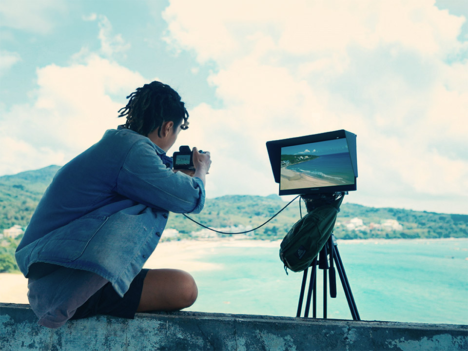 Créateur prévisualisant les prises de vue en extérieur à l'aide d'un écran portable haute résolution.